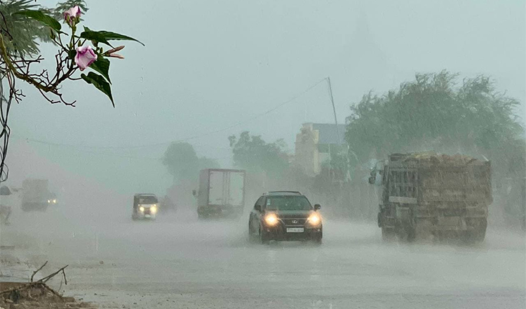 雨季のスコールの中、ヘッドライトを点けて走る車とトラック